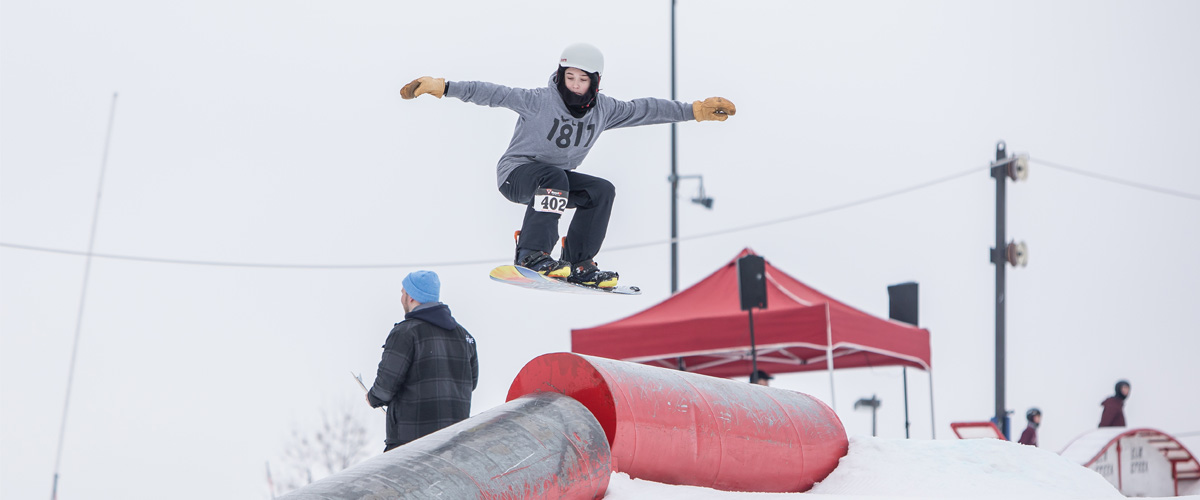 A snowboarder in mid-air over a pipe