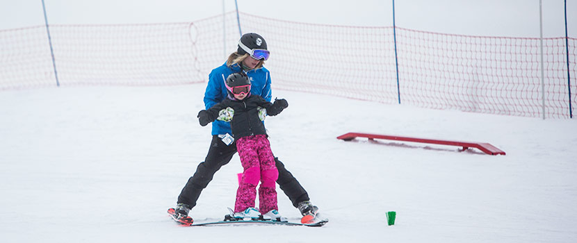 an instructor helping a young child learn to ski