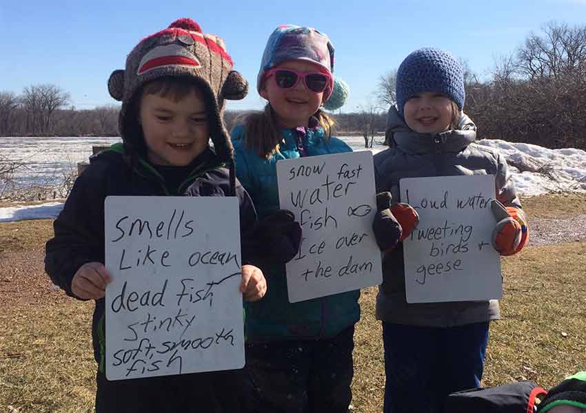 kids holding signs about what they think the river smells like