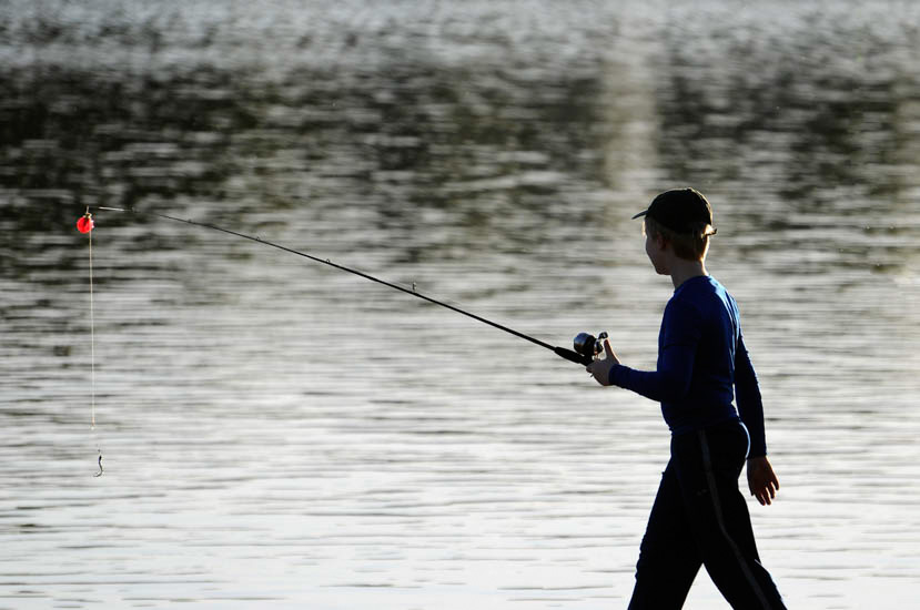 Boy with fishing pole on lakeshore