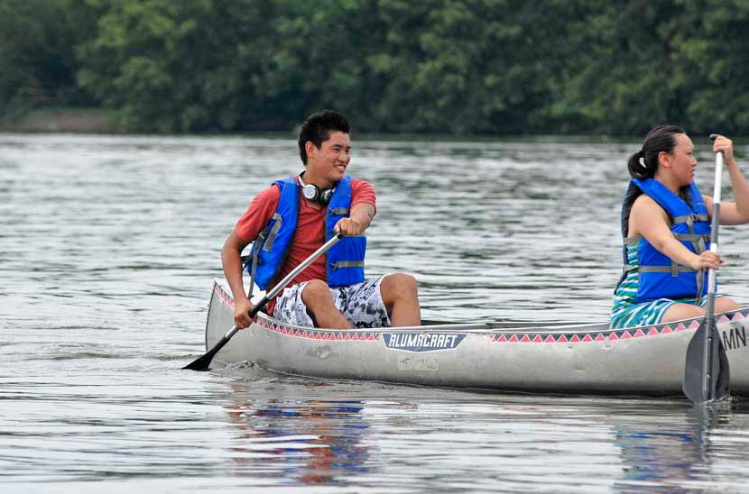 Kids paddle the river in canoes