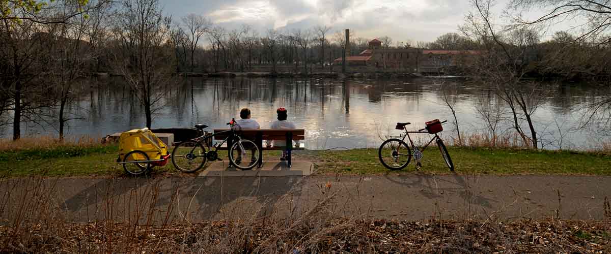 Bikers resting on a bench viewing the river