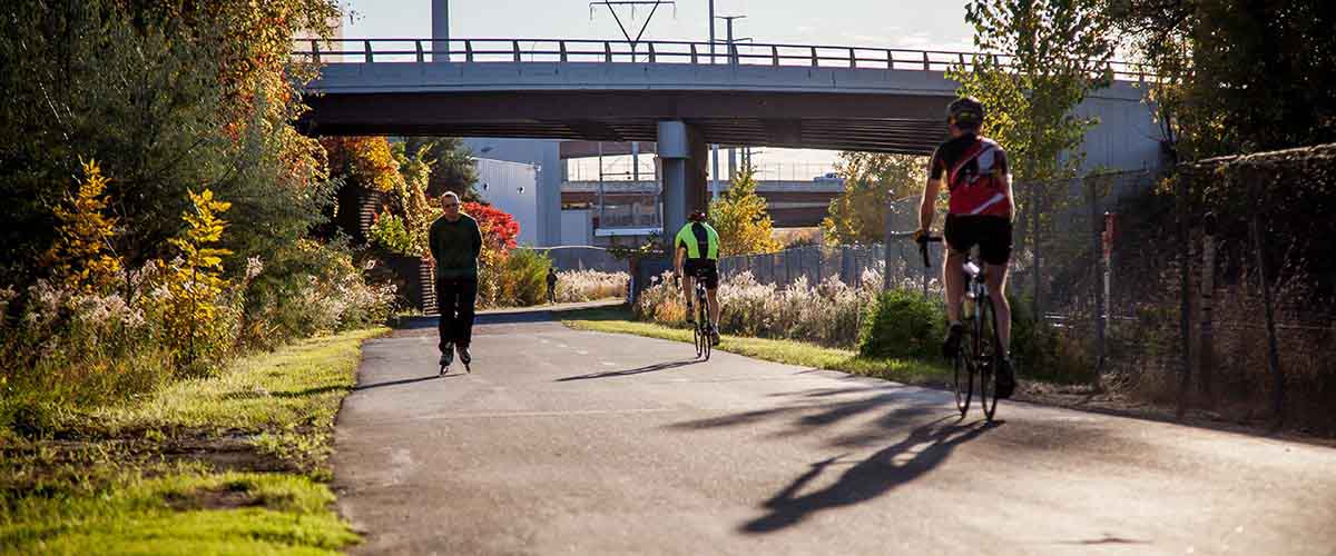 Biker and inline skater passing under bridge