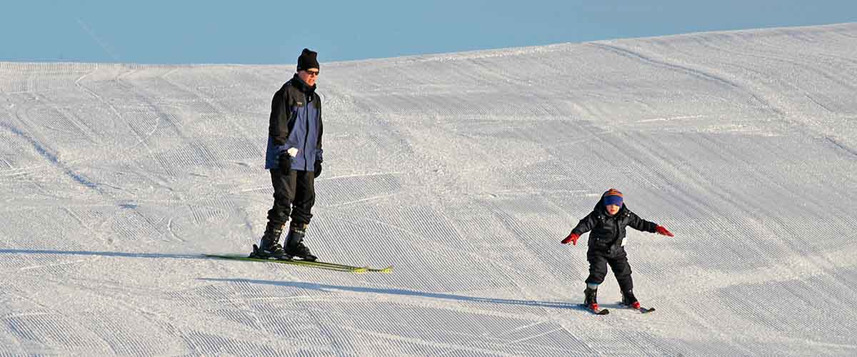 Adult and child on freshly groomed hill