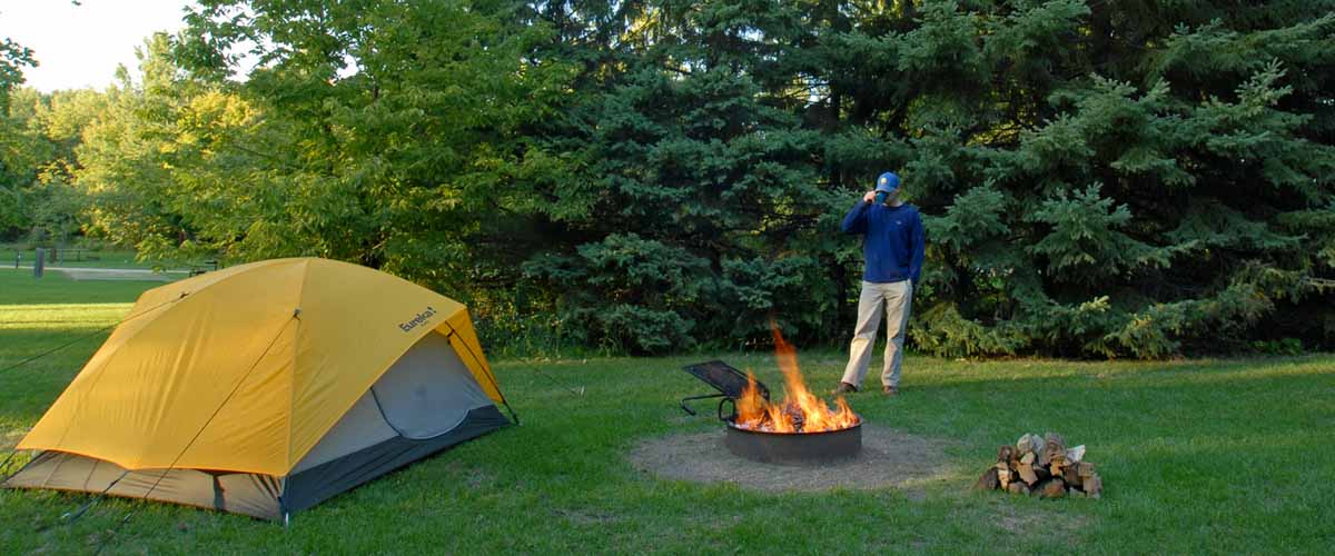 Camper near tent and bonfire