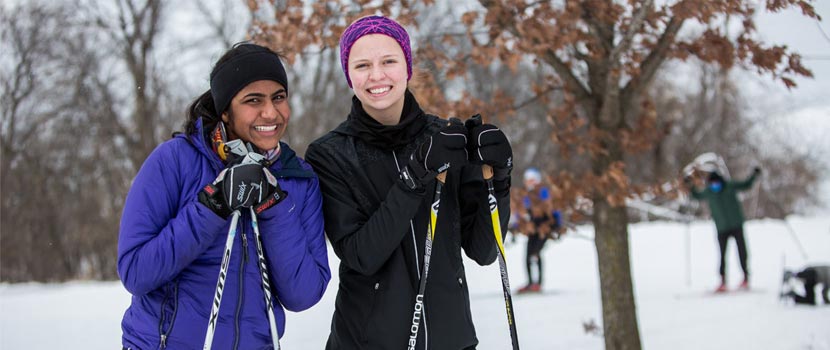 Two women smiling and holding cross-country ski poles.