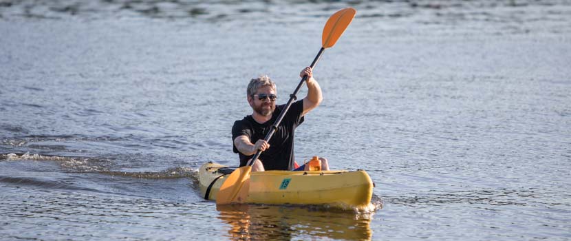 a man paddling in a yellow kayak