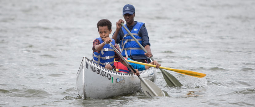 a teen canoeing with a child
