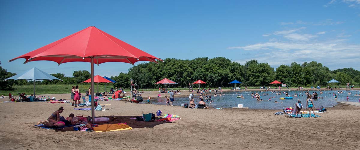 elm creek swim pond with a large red umbrella in the foreground