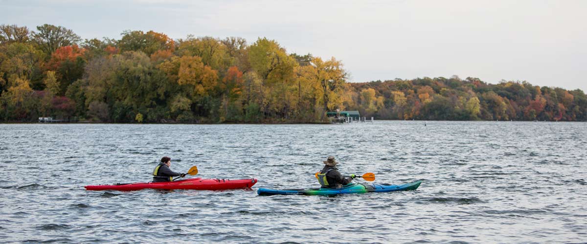 to kayakers paddling on a lake in the fall.