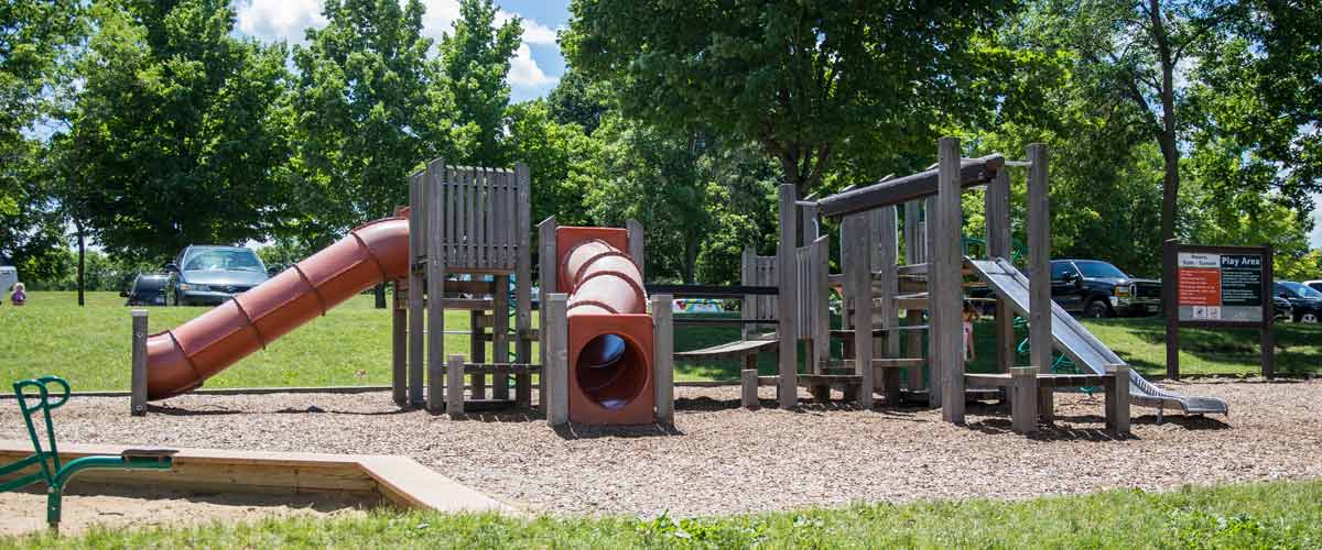 a wooden play area with red slides.