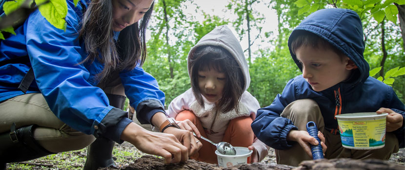 two kids learning from a naturalist outdoors in the spring.