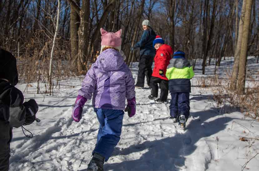 kids hiking in the snow through the woods