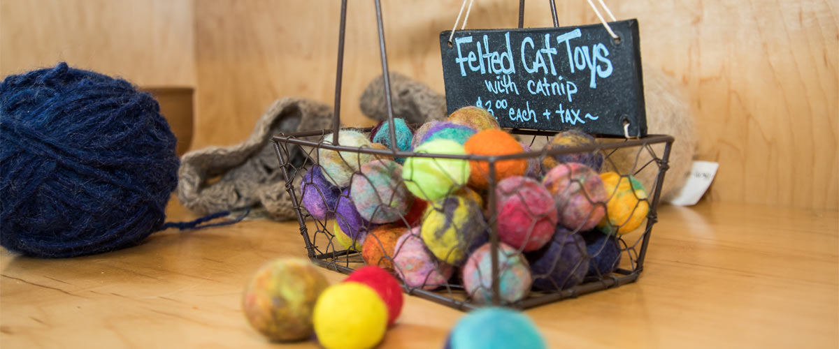 A wire basket with colorful felted cat toys.