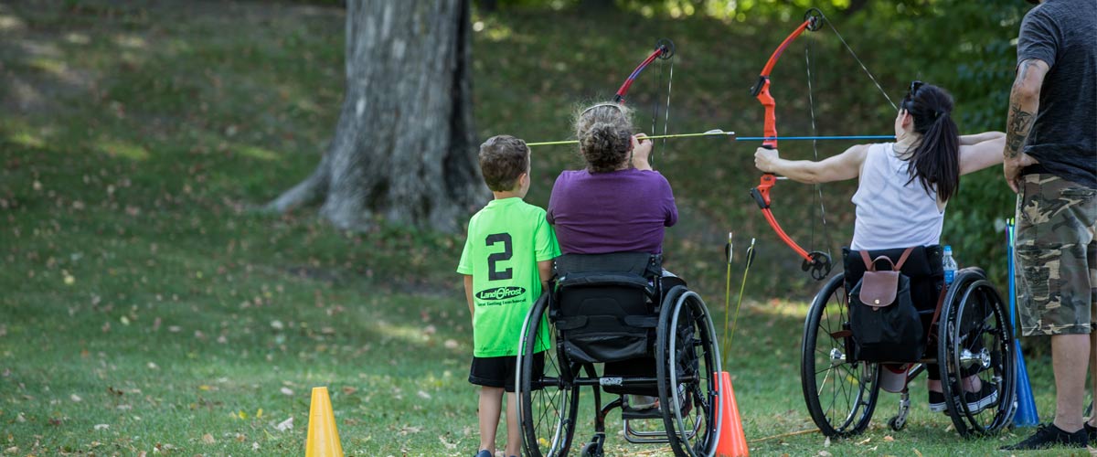 a woman shooting a bow and arrow from her wheelchair.