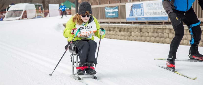 a woman racing on adapted cross-country skis.