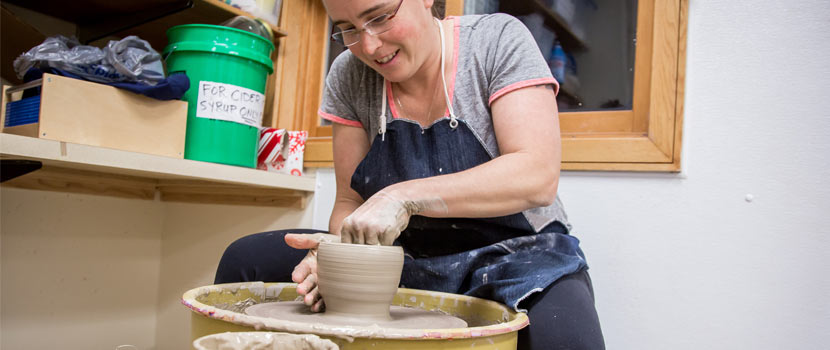 a woman making pottery on a wheel.