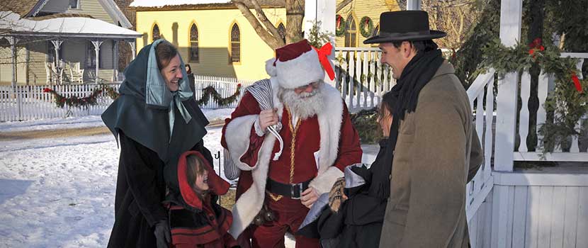 a man dressed as Santa Claus greeting a family 1800s costumed characters