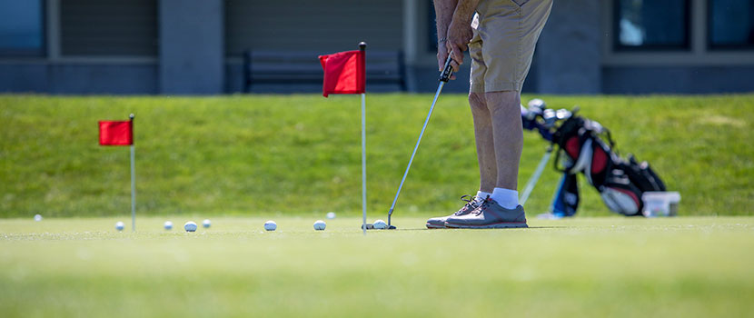 the legs of a person on a putting green setting up to putt. 