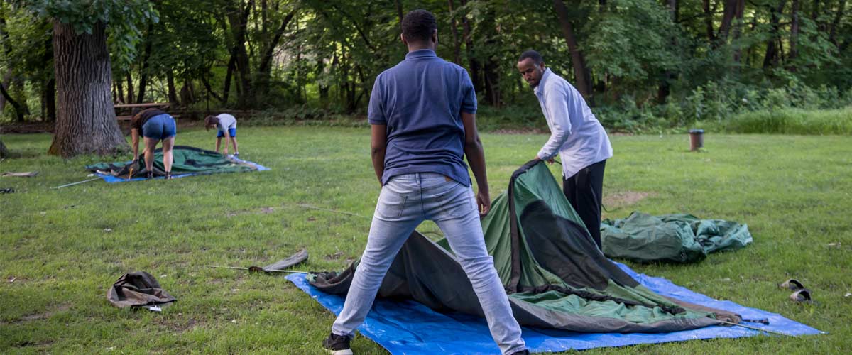two men work together to set up a green tent.