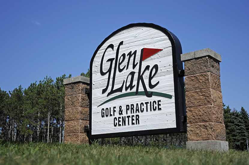 A white sign made of wood and brick says Glen Lake Golf and Practice Center