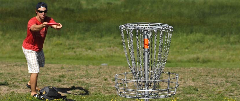 A man aims a disc at a disc golf goal. 