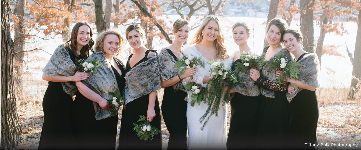 A bride poses with her bridesmaids outside.