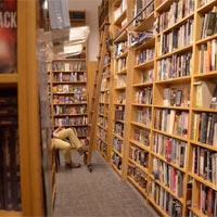 A person's legs stick out in the aisle at a bookstore.