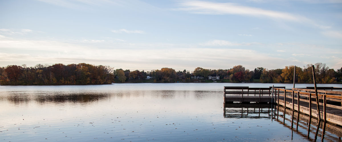 A wooden fishing pier floats on a lake in the fall.