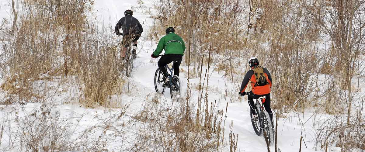 Three mountain bikers on a snowy trail.