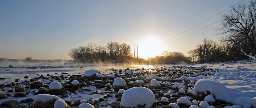 sunrise on the horizon with snow-covered rocks in the foreground
