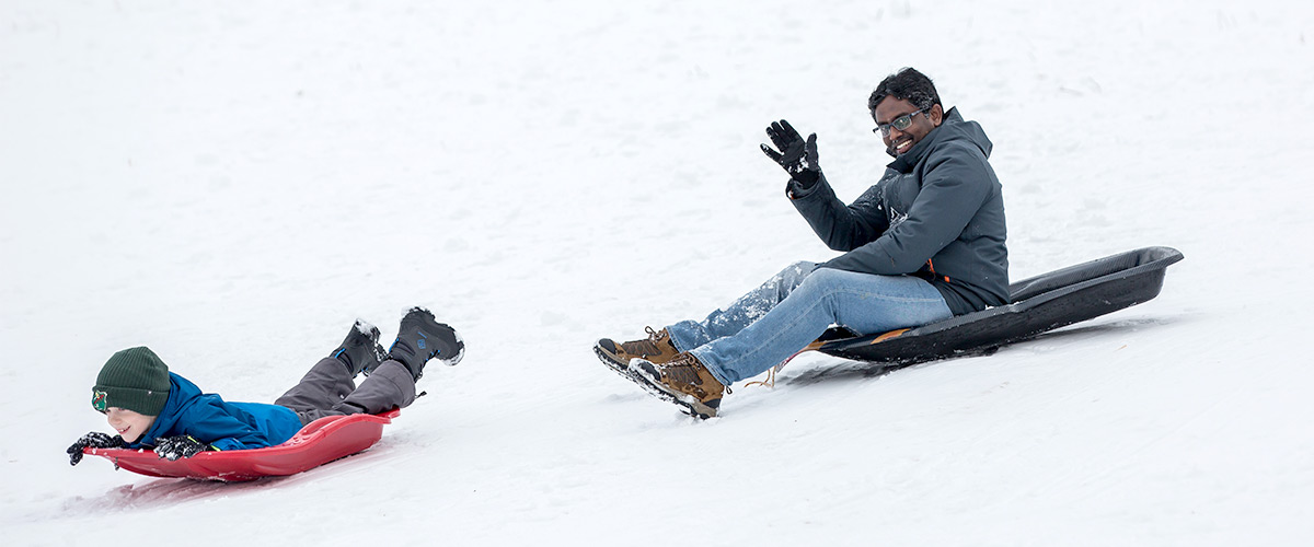 two people sledding down a snowy hill