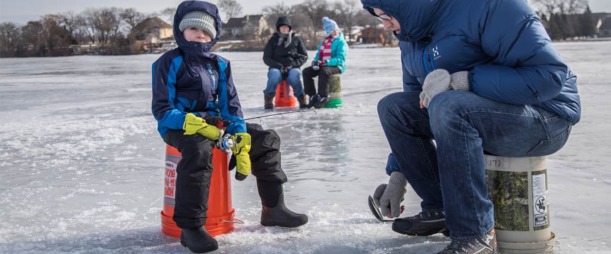 A boy and his father go ice fishing.