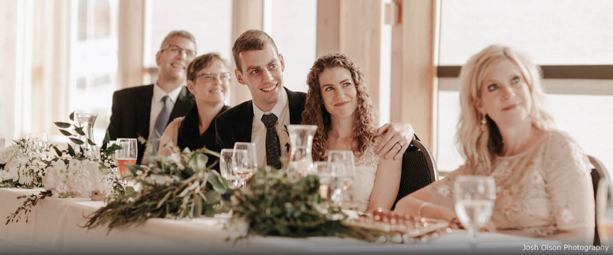A wedding party smiles at the head table. 