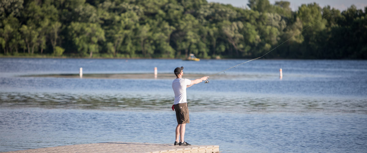A man casts a fishing line from a pier.