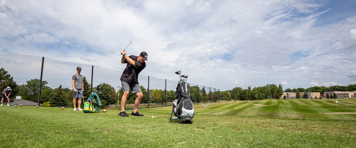 A man practices his swing at a driving range.