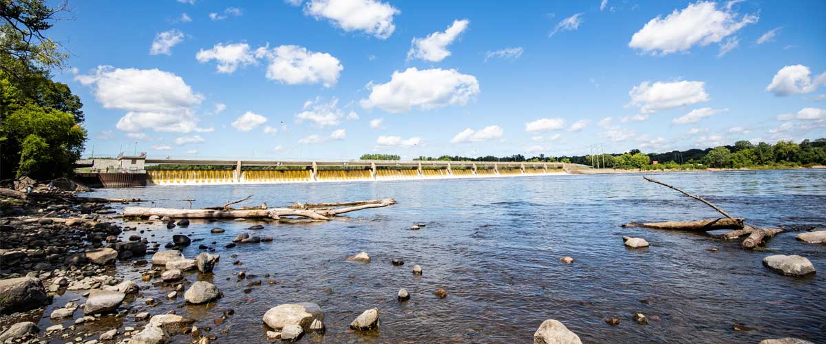The Mississippi River flows over the Coon Rapids Dam on a sunny summer day.