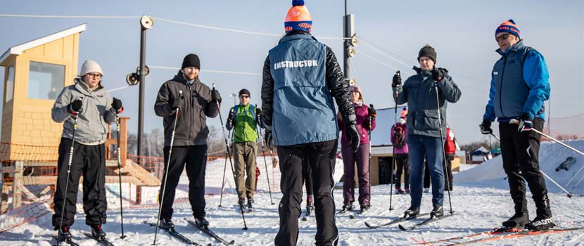 An instructor teaches a small group of people how to cross-country ski.
