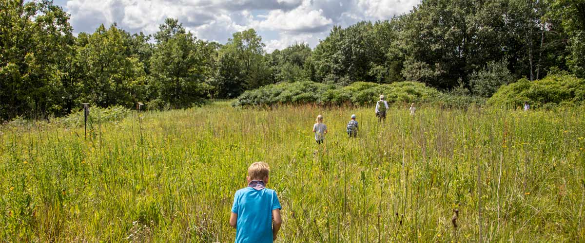 A naturalist leads a group of kids through a prairie.