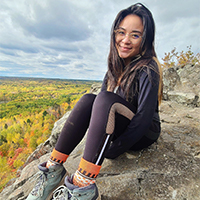 annabella lau sitting at an overlook of fall forests