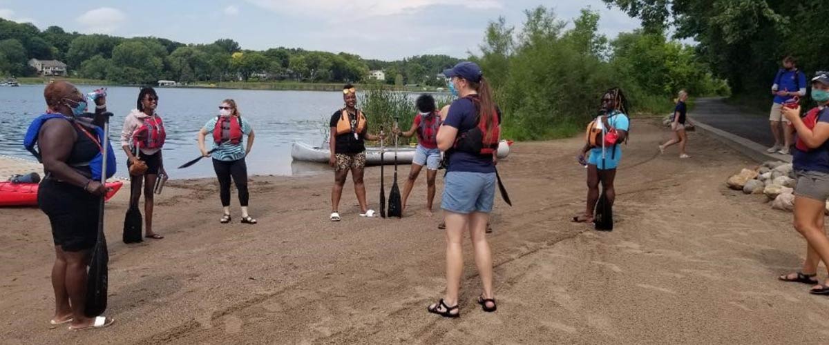 A group of people gets a canoe lesson from a Three Rivers staff person at Fish Lake Regional Park. 
