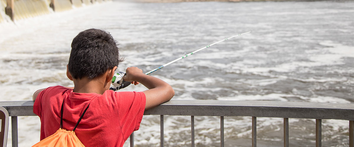 A person wearing a red shirt is fishing off a platform overlooking the Mississippi River.