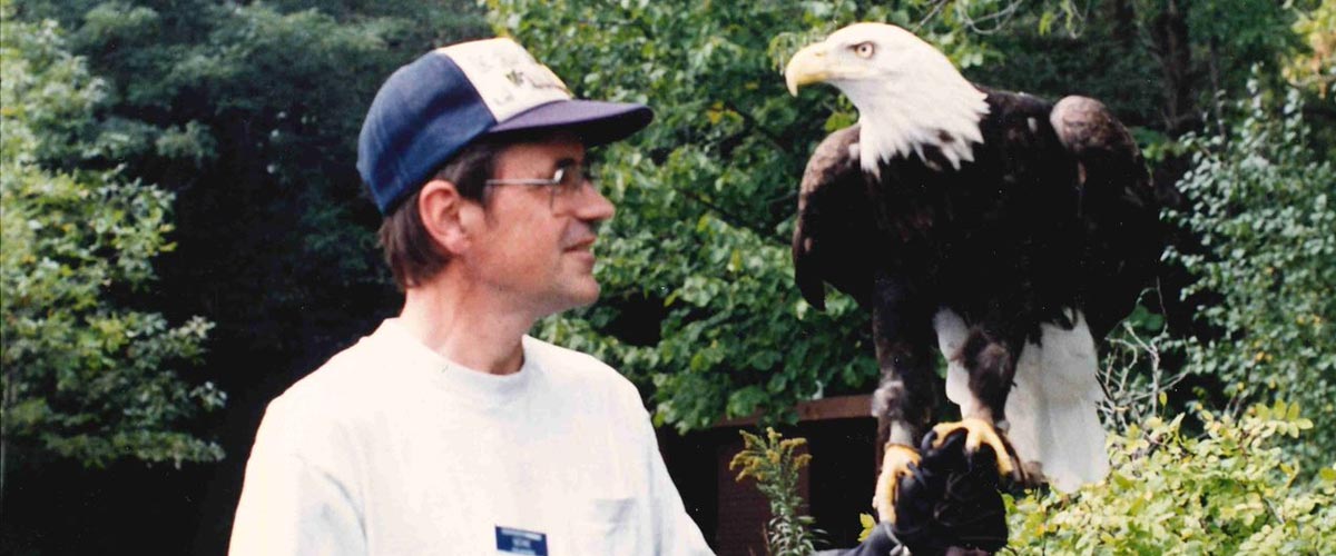 Three Rivers volunteer Gene Lau looks at a bald eagle that's perched on his hand.