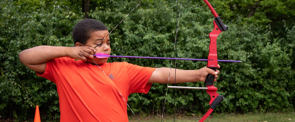 A boy aims a bow and arrow.
