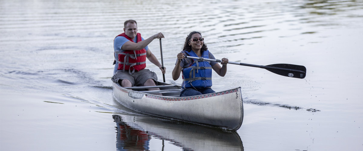A man and a woman paddle a canoe together on Silver Lake in Silverwood Park.