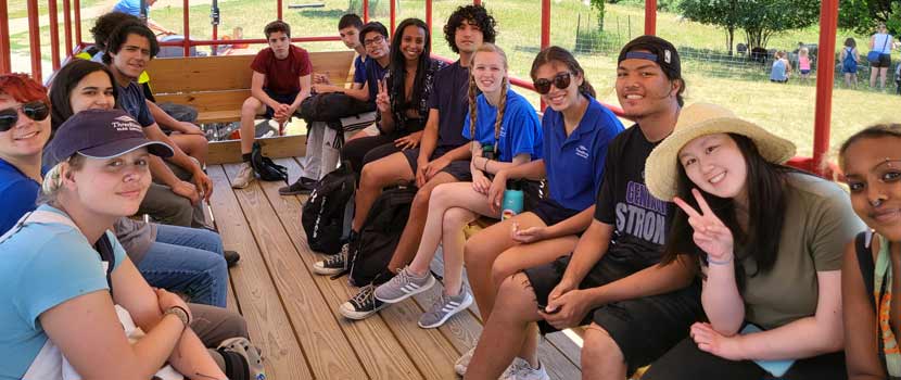 A photo of a group of Pathways interns sitting on benches smile for the camera.