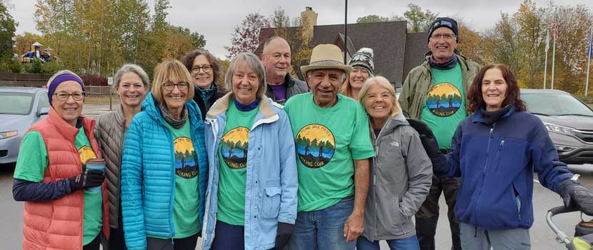 A group of Hyland Sole Mates hikers pose in a parking lot, many wearing green shirts with the Hyland Sole Mates logo on it.