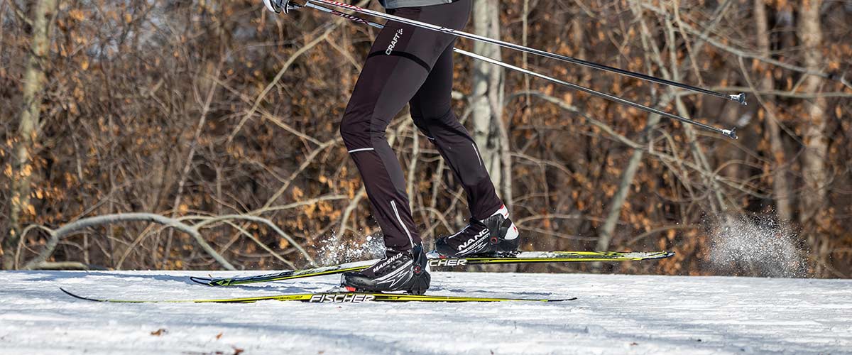 A photo of a cross-country skier skiing through the woods.