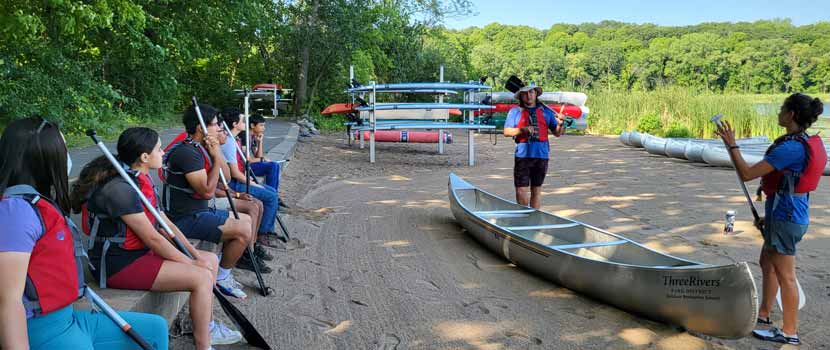 A group of Pathways interns watch canoeing instruction.