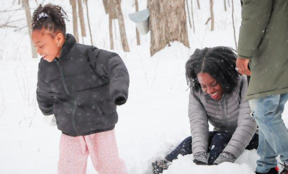 InnovativeSOULutions participants in a maple syruping program at Eastman Nature Center play in the snow in March 2023.